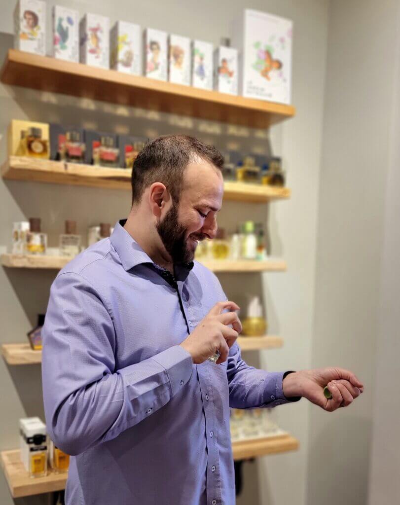 Nir Guy dans sont shop / il sourie / il se spray le parfum 50ml Mousse Arashiyam du Jardin Retrouvé