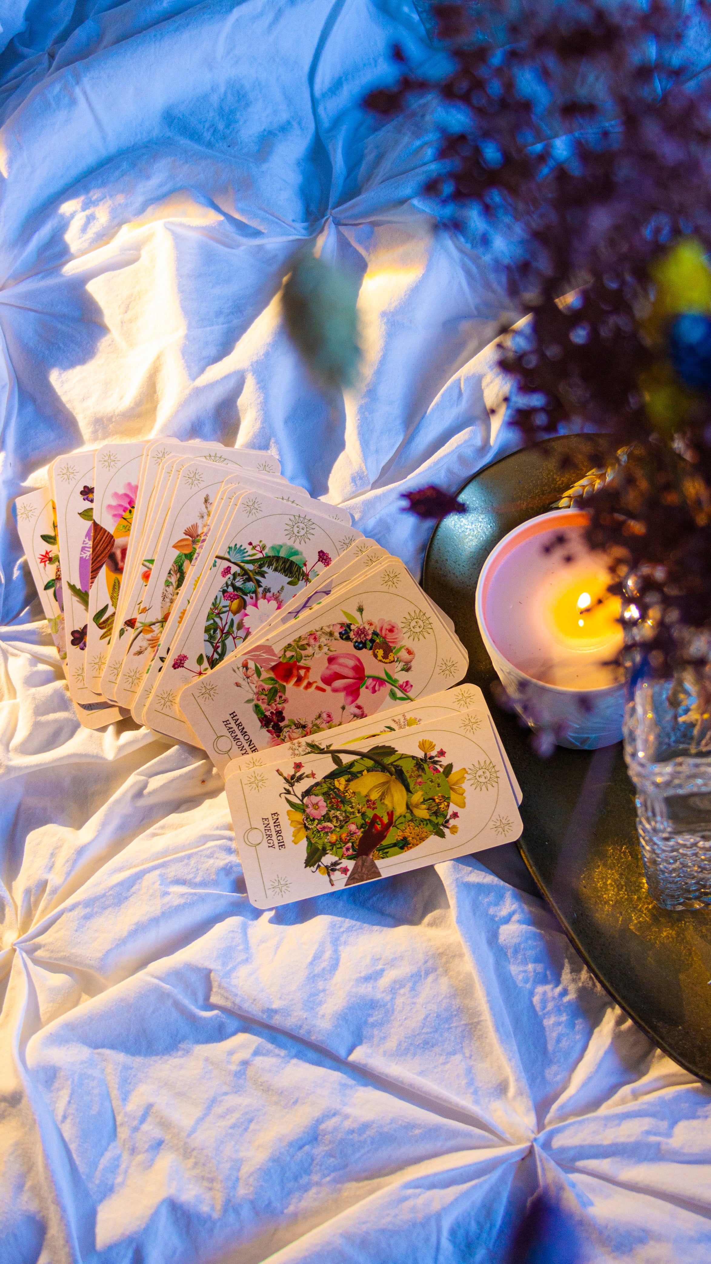 Les carte de L'Oracle du Jardin Retrouvé  sur un drap prêt d'une bougie, bien-être